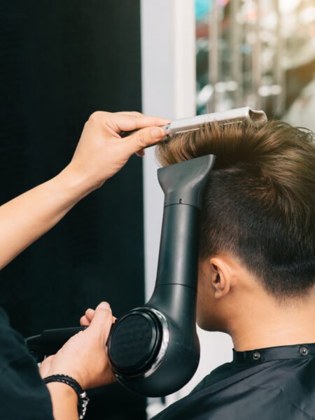 Close-up image of hairdresser blowing out hair of client with fan